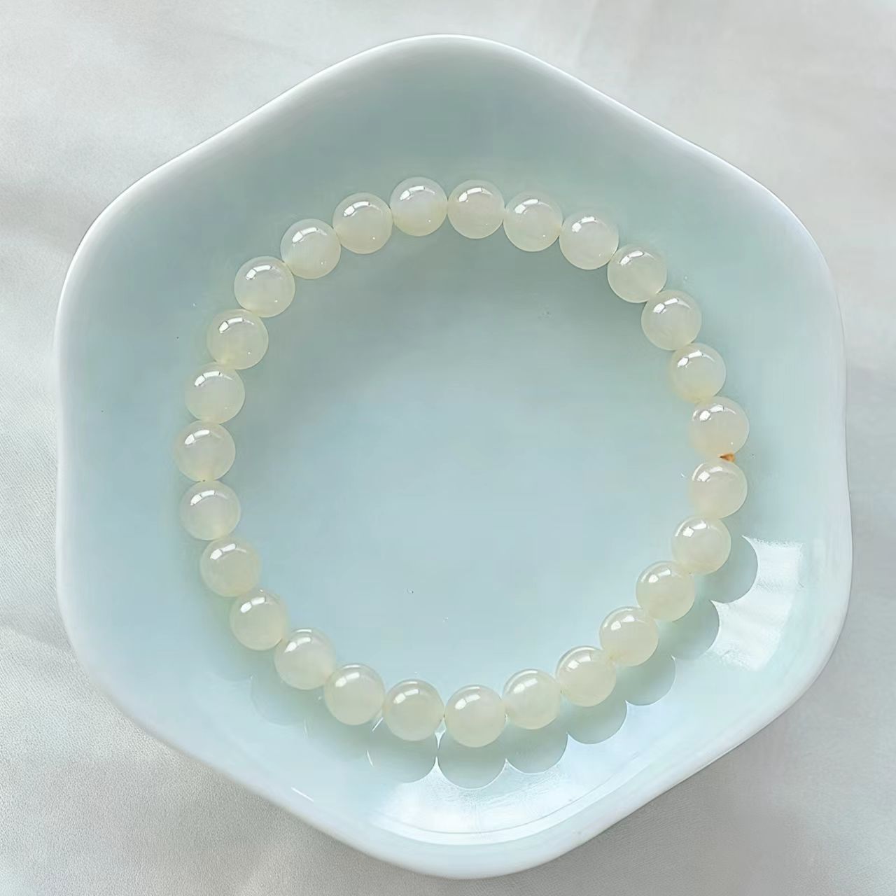 Pearl bracelet on a light blue dish with a white background