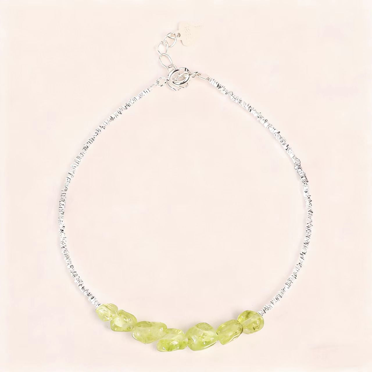 Necklace with green beads on a light pink background