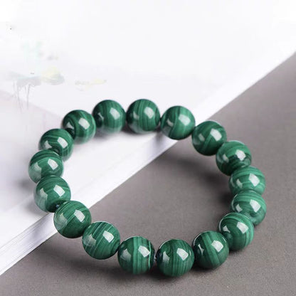 Green beaded bracelet on a gray surface with a white background