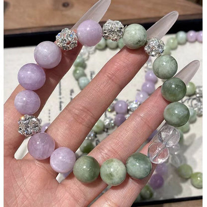 Hand holding a bracelet with green and purple beads and silver accents.