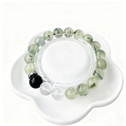 Green beaded bracelet with a black bead on a white dish