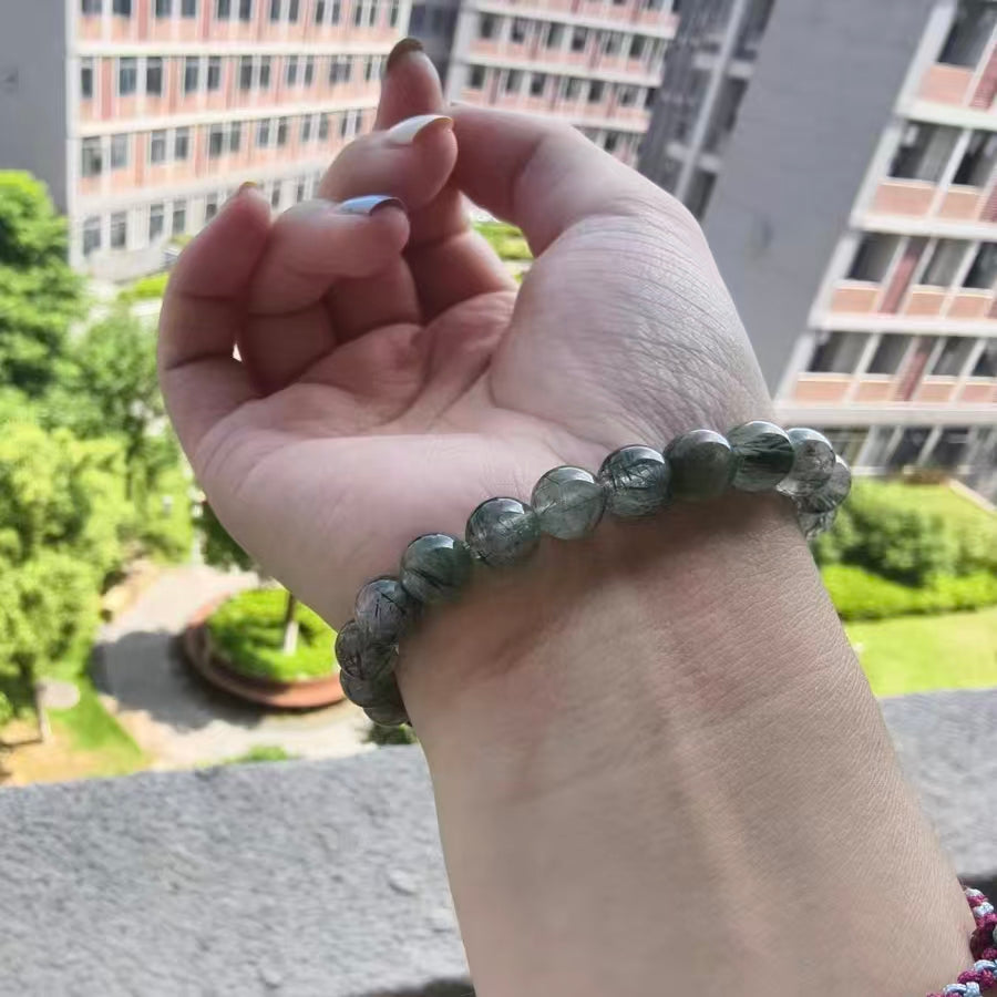 Hand wearing a bracelet with a blurred outdoor background