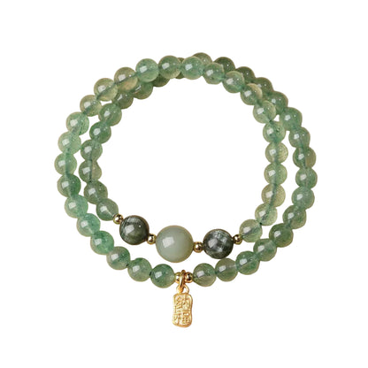 Stack of green beaded bracelets with a gold charm on a beige background