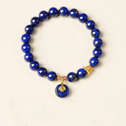 Blue beaded bracelet with a gold charm on a white background