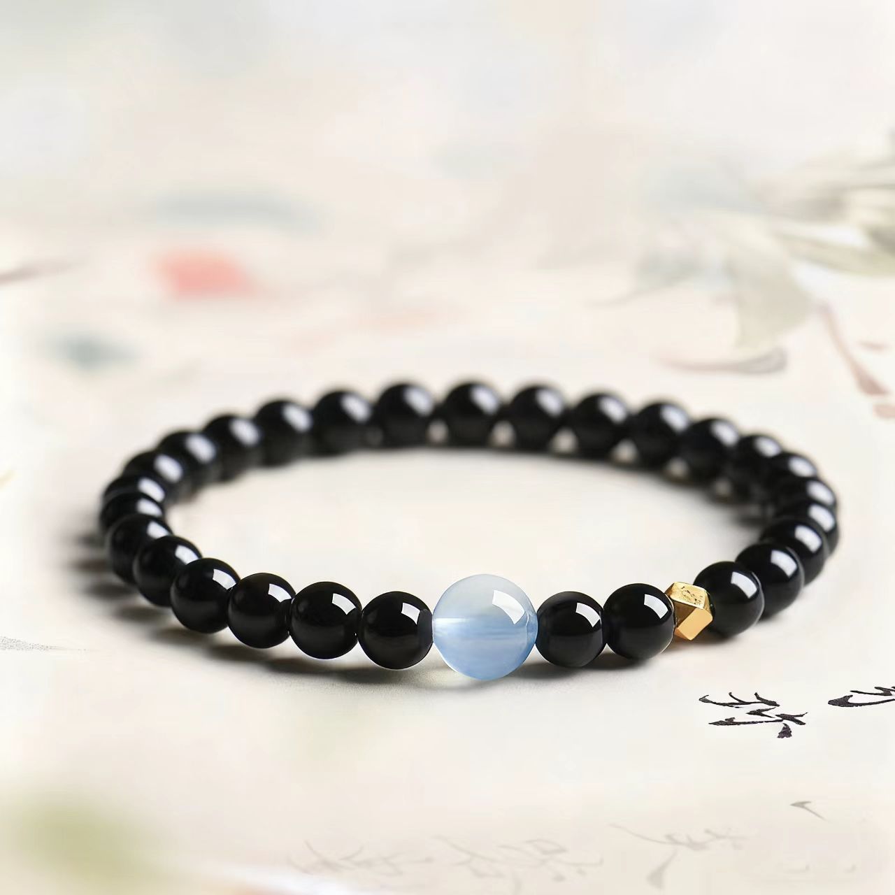 Black beaded bracelet with a blue cat's eye stone on a light background