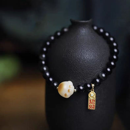 Black beaded bracelet with a gold charm on a dark background