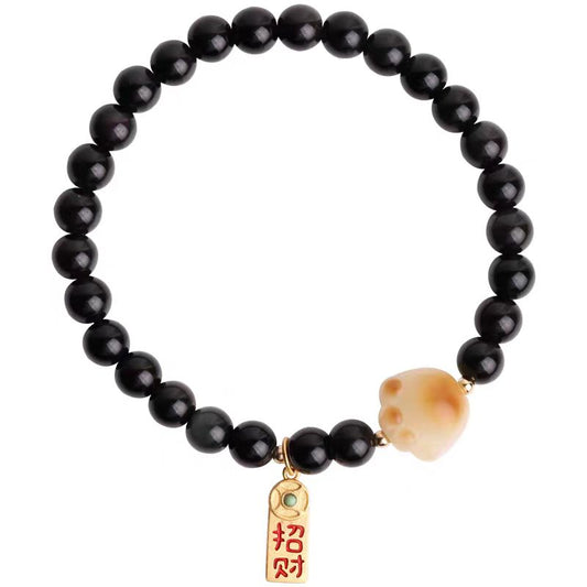 Black beaded bracelet with a gold charm and peach stone on a white background
