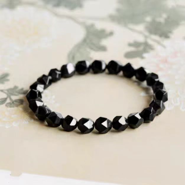 Black beaded bracelet on a floral-patterned fabric background