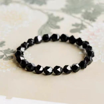 Black beaded bracelet on a floral-patterned fabric background