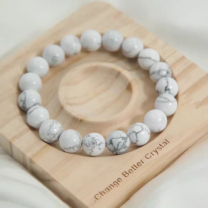 White beaded bracelet on a wooden block with 'Change Better Crystal' text