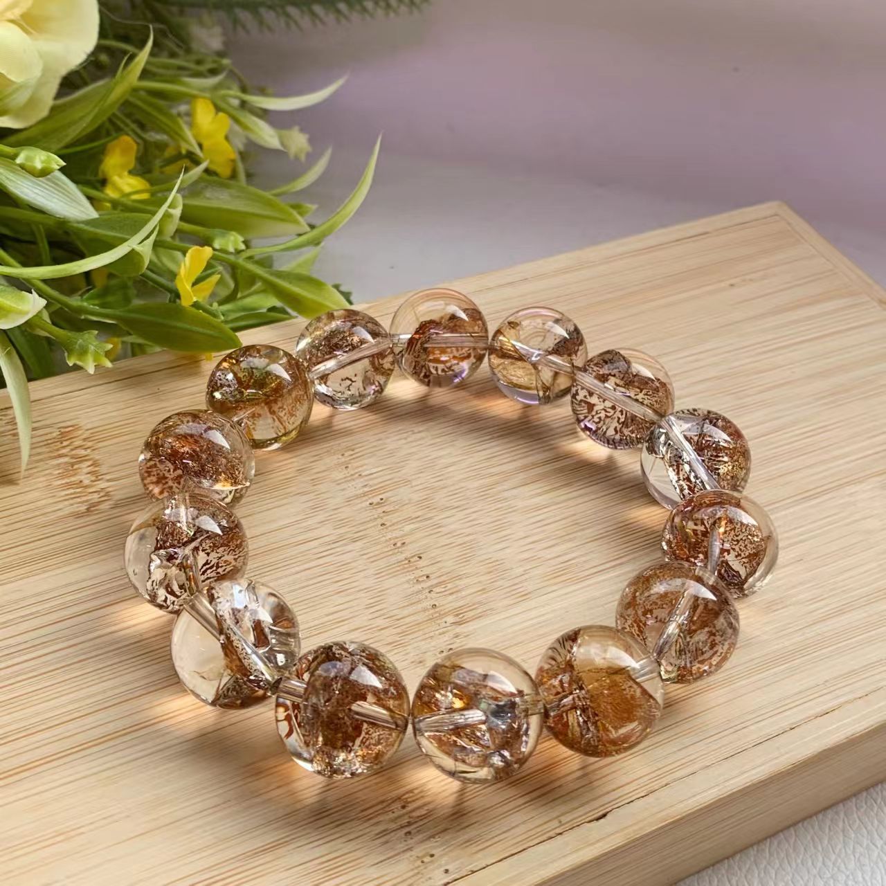 Brown beaded bracelet on a wooden surface with flowers in the background