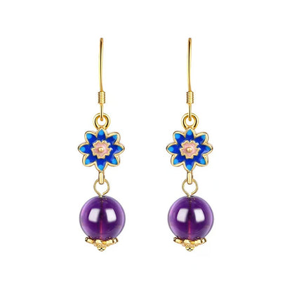 Pair of earrings with blue floral tops and purple beads on a white background