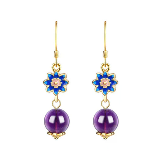 Pair of earrings with blue floral tops and purple beads on a white background
