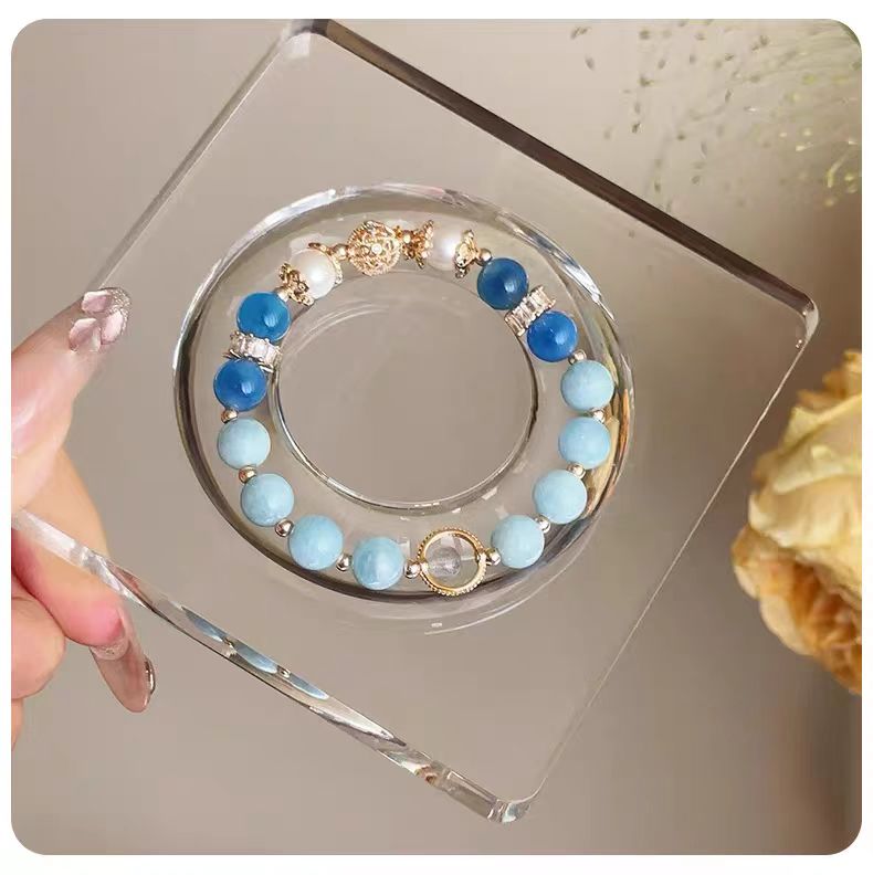 Blue and gold beaded bracelet on a clear stand with a neutral background