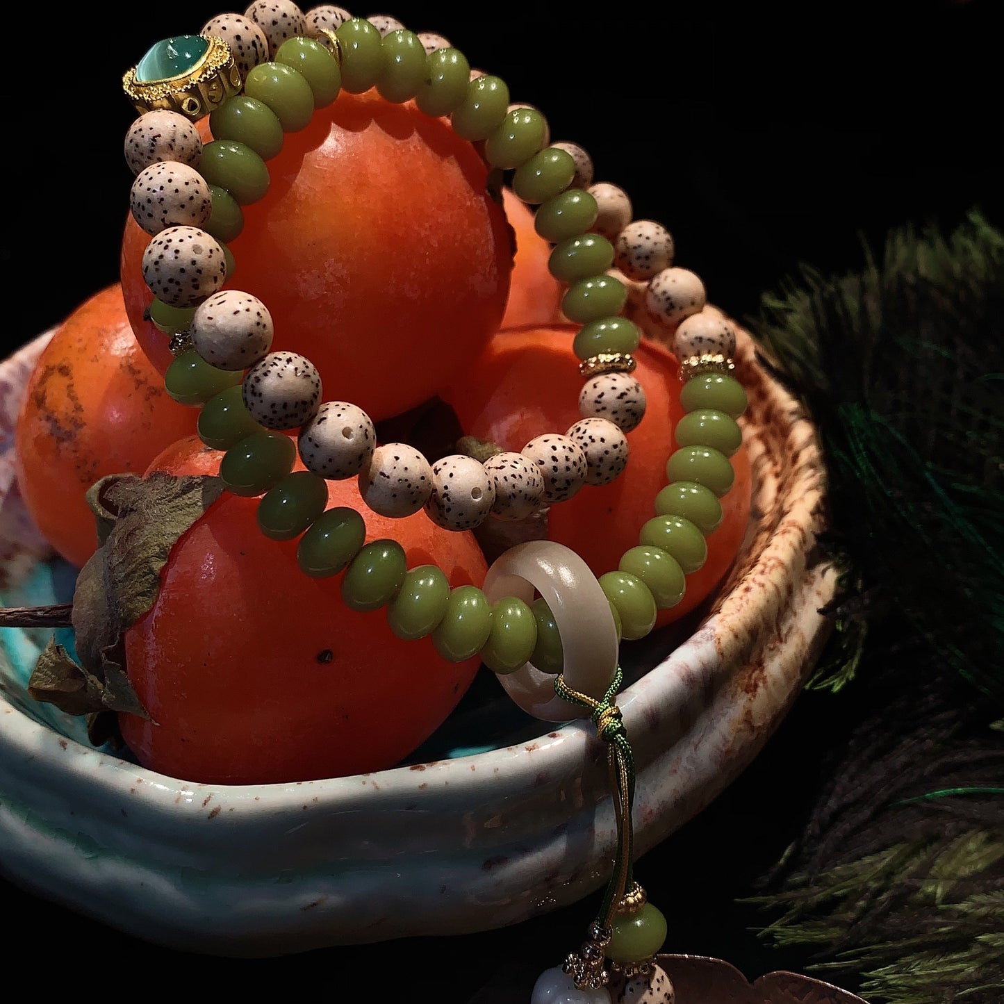 Green and white beaded bracelet on persimmons with a dark background
