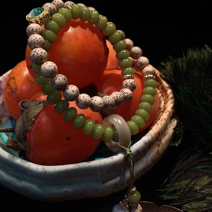 Green and white beaded bracelet on persimmons with a dark background