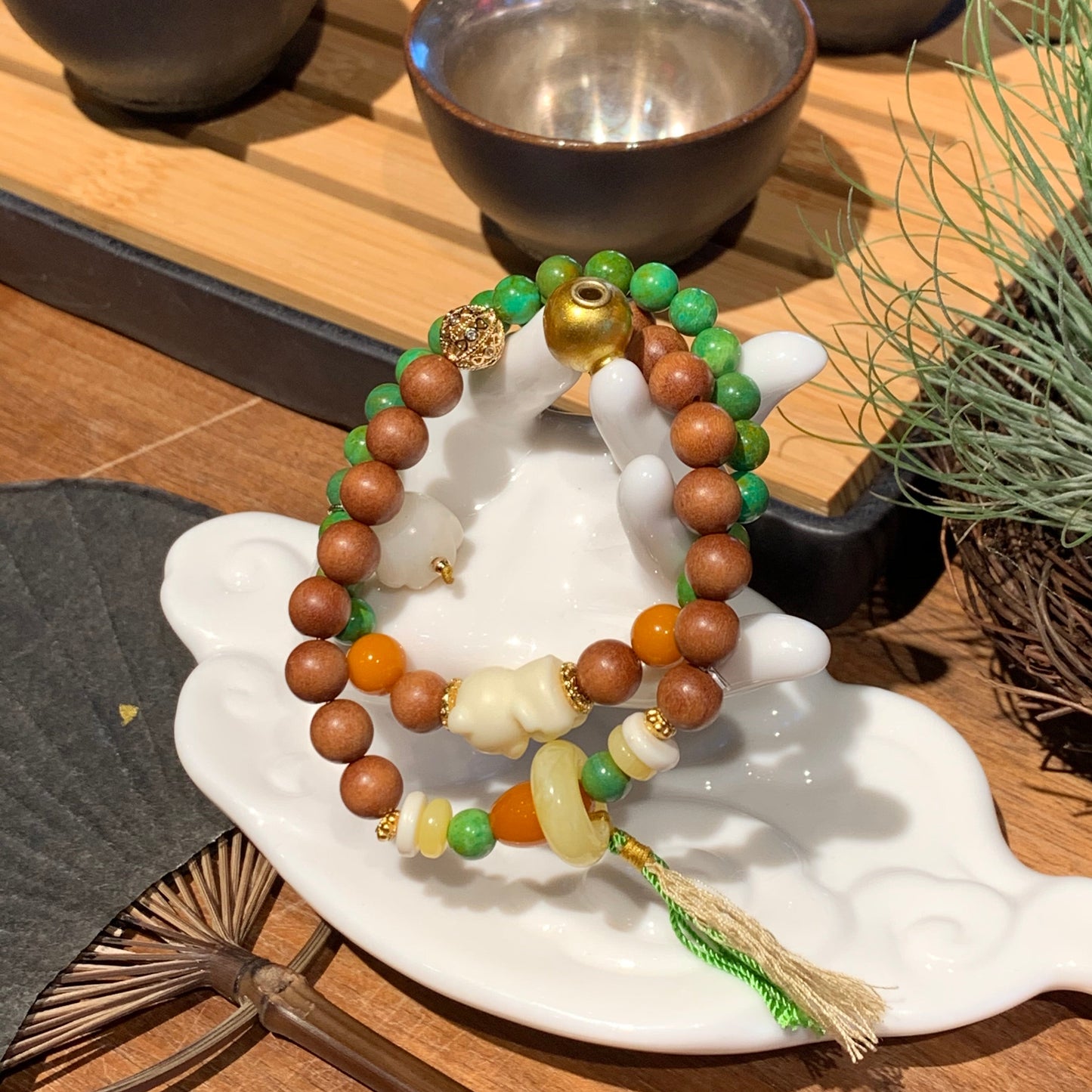 Colorful beaded bracelet on a white dish with decorative elements on a wooden surface